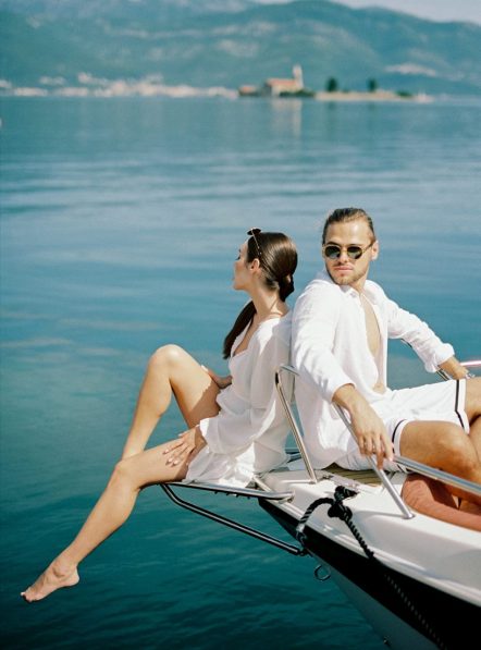 Man and woman are sitting on the bow of a yacht, leaning their backs and looking in different directions. High quality photo